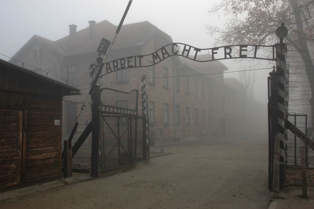 Hitlerowskie pozdrowienie na tle obozowej bramy